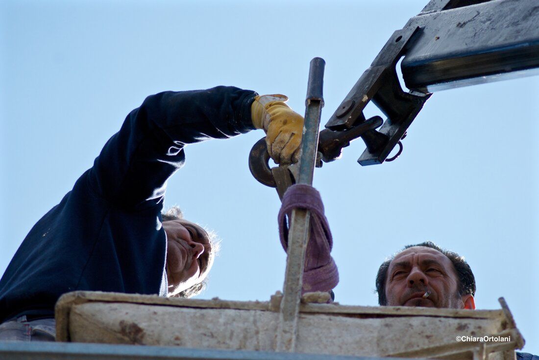 Operai al lavoro con un argano contro il cielo azzurro