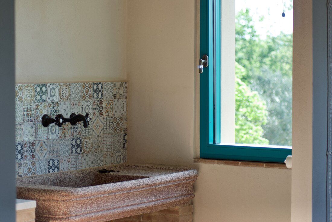 Stone sink with decorated tiles and a window