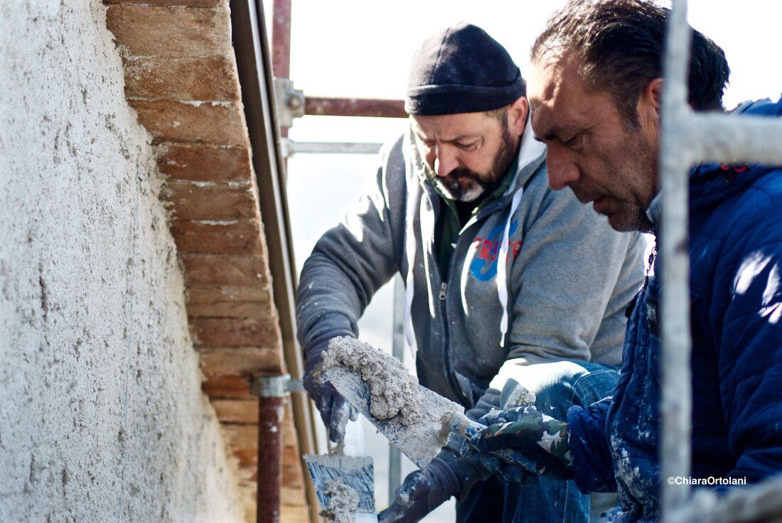 Due muratori al lavoro su una parete intonacata