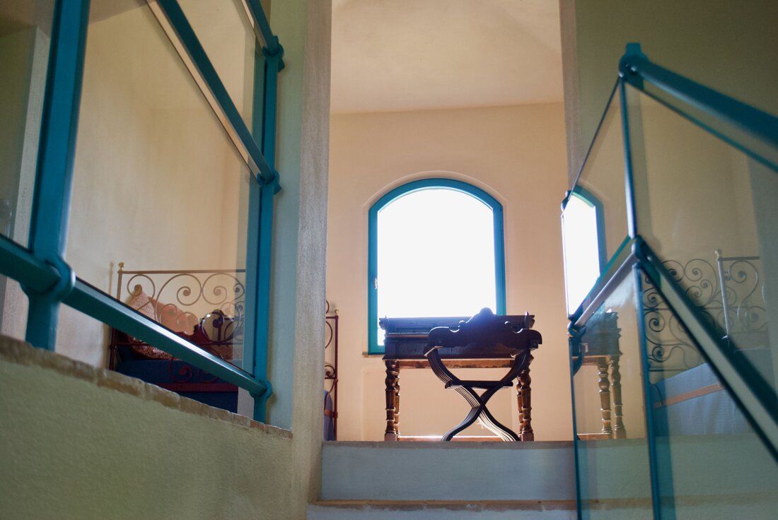 Arched window and writing desk seen between teal railings
